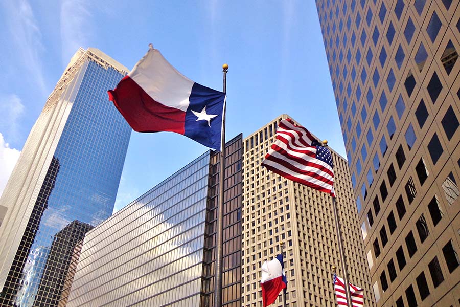 Contact - View of Texas and American Flags in Front of Modern Commercial Buildings in Houston Texas