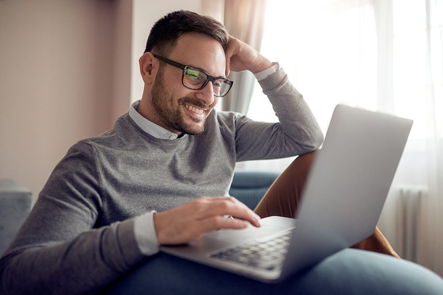 Blog - Friendly Man Sitting Down Reading on His Laptop